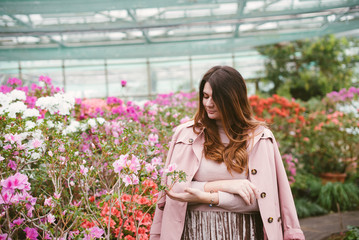 Beautiful girl in the greenhouse of the botanical garden among the azaleas