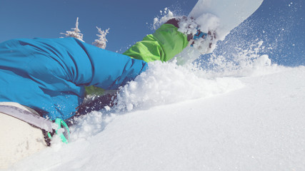 CLOSE UP: Professional snowboarder trips and falls flat on his face into snow.