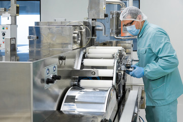 Pharmacy industry factory man worker in protective clothing in sterile working conditions operating...