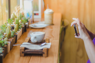 Beautiful woman taking a coffee picture in a cafe alone.