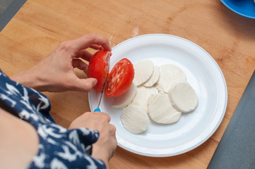 woman preparing salad of tomatoes and buffalo cheese