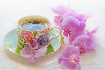 Morning cup of coffee. Sprig of orchid on the table