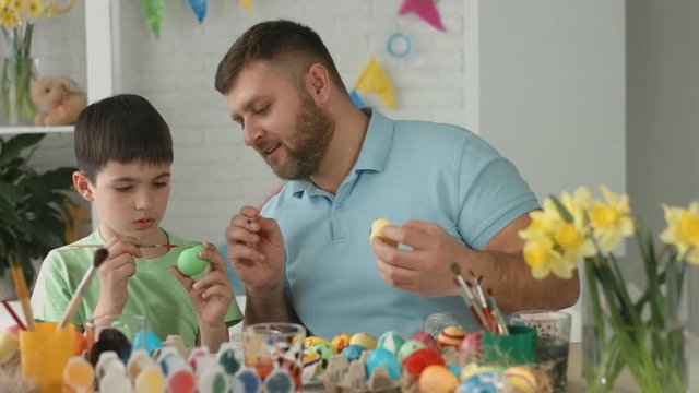 Father and son painting colorful eggs