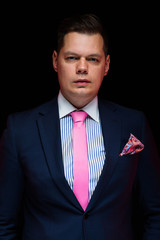 Portrait of confident handsome businessman looking in camera on black background