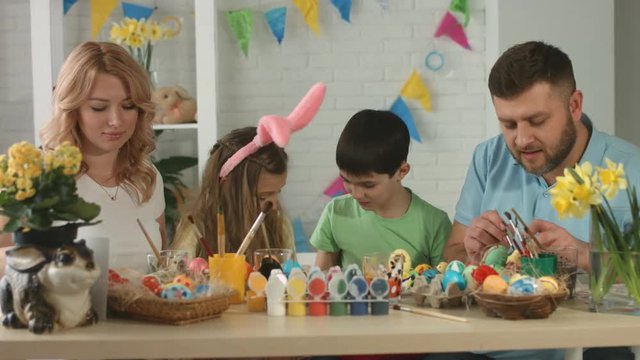 Family having fun while painting and decorating eggs for holiday