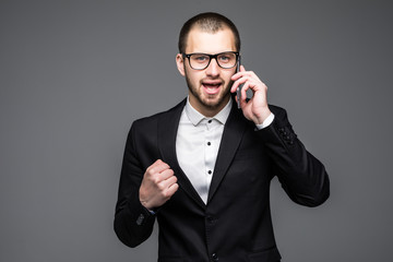 Happy businessman talking on the phone and celebrating his success over gray background