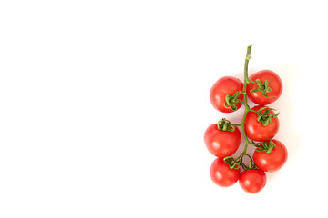 Branch of beautiful juicy organic red cherry tomatoes on white background. Top view of shiny polished glossy vegetables. Clean eating concept. Vegetarian vegan summer detox diet. Copy space, flat lay.