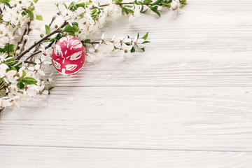 happy Easter concept. stylish painted egg on rustic wooden background with spring flowers and willow branches. seasons greeting card. space for text. modern colorful easter eggs