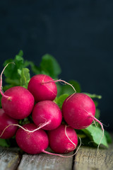 Branch of fresh radish over rustic old boards. The concept of a harvest and organic food. Copy space.