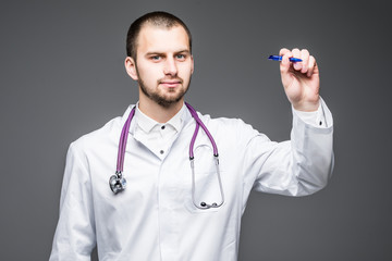 Young male doctor writing something on screen isolated over a gray background