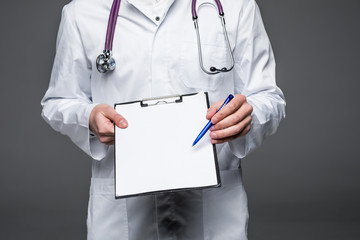 Close-up cropped image of a male doctor holding a chart with copy space offering to sign it...
