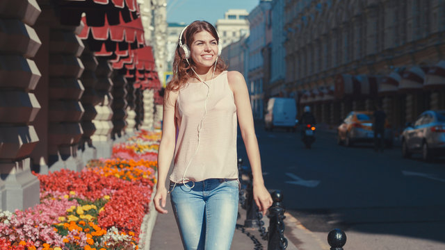 Smiling young girl listen to music on the street