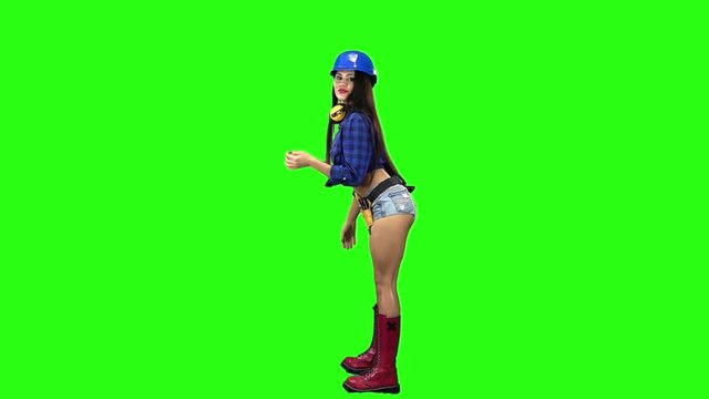 Side view of girl wearing helmet and shorts erotically dancing on green background. Slow motion