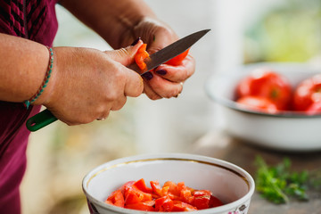 the cooking process for fresh vegetable salad,  healthy nutrition, women's hands cut cucumbers and tomatoes