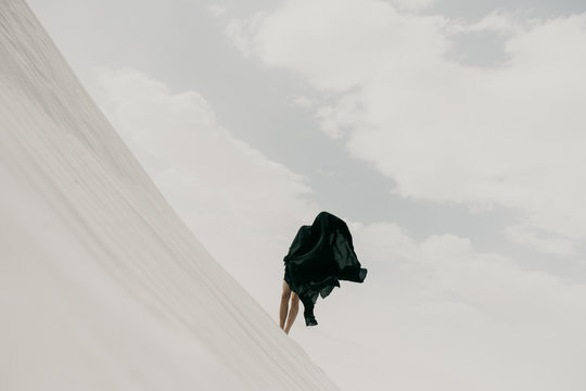 Dark mysterious black cloth blowing in the wind in the desolate desert hiding a human silhouette