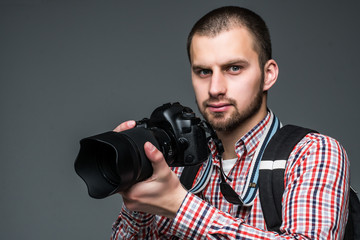 Portrait of male photographer with professional camera isolated on gray background