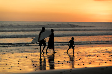 Happy family father, mother, son with fun along sunset sea surf on black © Louis-Paul Photo