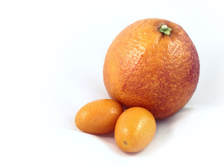 Two kumquats and a blood orange on a white background