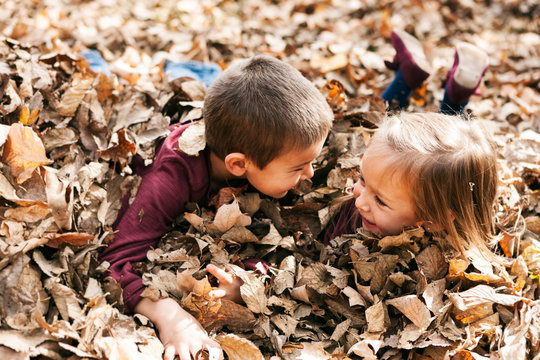 Autumn: Kids Playing In Big Leaf Pile