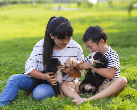little asian boy holding his puppy sitting with his mother on th