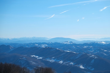 Beautiful view of umbria valley in Italy on a snowy winter morning with fog covering the mountains under a blue sky