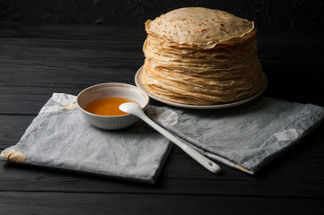 Homemade pancakes with honey and walnuts, vintage white plate, dipper, dark wooden table.