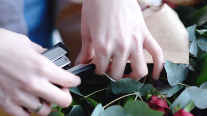 Obraz na płótnie Canvas Florist using stapler to attach a craft paper. Close up view of arranging bouquet