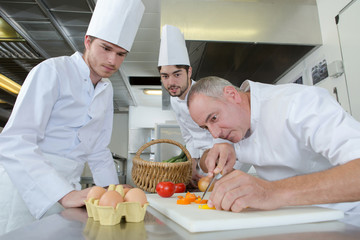 apprentices watching chief chef garnishing a dish