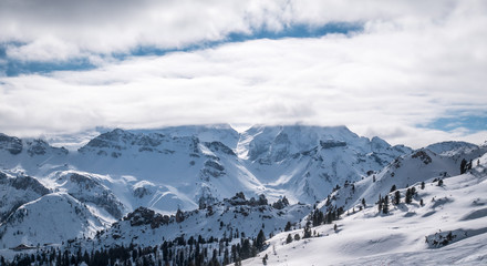 Panorama over snowy hills in the alps. Winter landscape. Low clouds or myst is covering the top of the moutains.