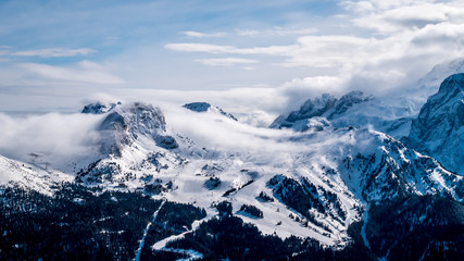 Obraz premium Clouds or mist coming in on the top of the hills in Canazei Alps, Italy. Ski slopes in Val di Fassa.