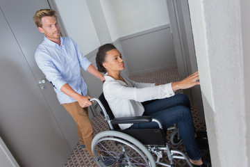 woman on wheelchair pressing elevator button
