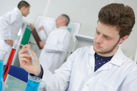 young man lab worker holding up test tubes