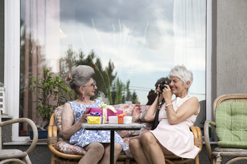 Mature woman taking a photo of her friend who is celebrating her Birthday