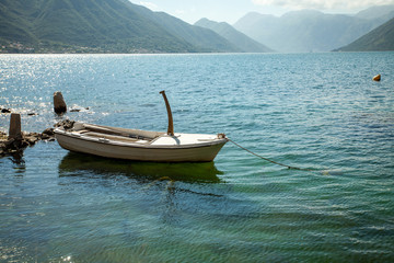 Fototapeta na wymiar Empty parked boat on the clear transparent water of turquoise color on the lake in the mountains