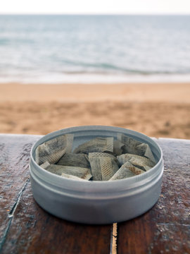 Swedish snus tobaco on a wood table in Thailand. Beach in background.