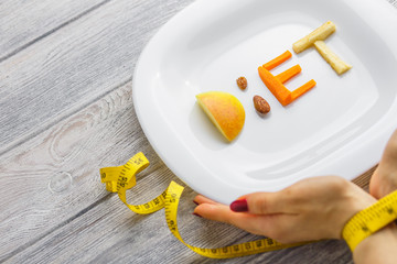 fruit on a plate of a word diet of apple, kiwi, carrots, nuts and raisins. healthy body concept