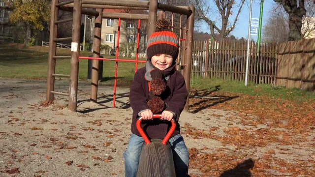 Happy smiling child lifting up to blue sky in playground seesaw, childhood joy