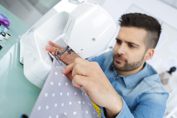 young man with sewing machine at home