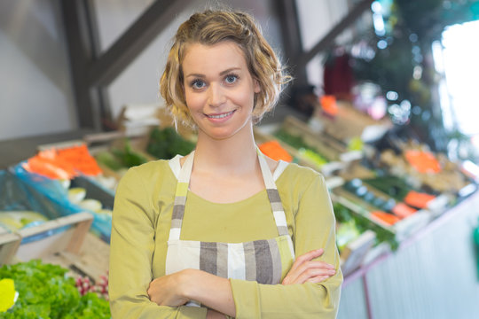 portrait of smiling woman in apron selling veggies