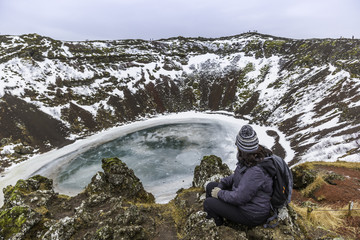 The winter colours of beautiful Kerio, or Kerid crater in western Iceland. Red volcanic rock, green mossy slopes and a circle of breaking ice in a turquoise lake