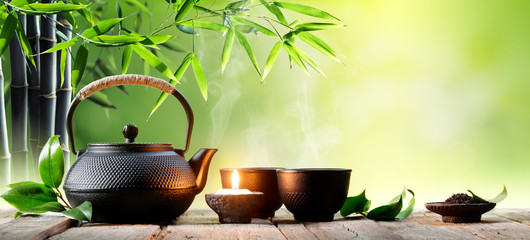 Fototapety  Azjatycki czajniczek i filiżanki z czarnego żelaza z liśćmi zielonej herbaty