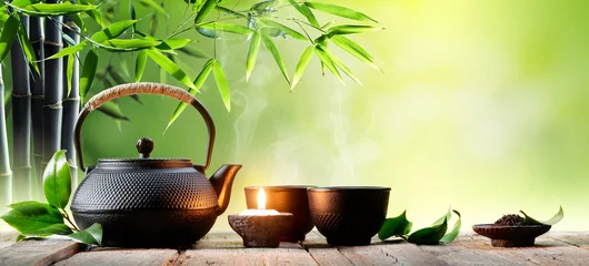 Papier Peint photo Theé Black Iron Asian Teapot and Cups With Green Tea Leaves  