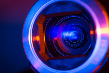 Video camera lens lit by blue and red neon light