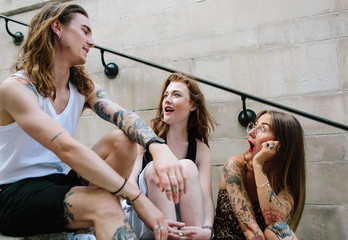 Three friends sitting together chatting and expressing surprise