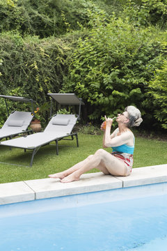 Cool progressive senior woman drinking a coktail in the garden