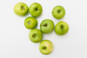 Flatlay with eight fresh, green-yellow Golden Smith or Granny Smith apples on white background