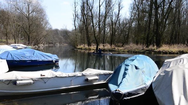 barche da fiume attraccate al molo coperte da teloni al primo sole dopo l'inverno
