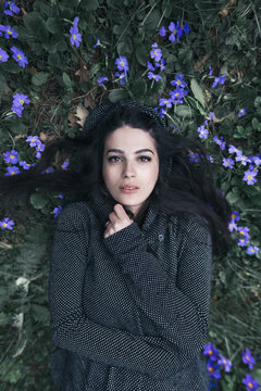 Portrait of a beautiful woman lying in violet flowers