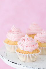 Cupcake decorated with pink buttercream on pastel pink background.