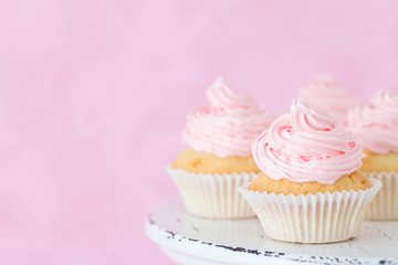 Cupcake decorated with pink buttercream on shabby shic stand on pastel beautiful pink background.